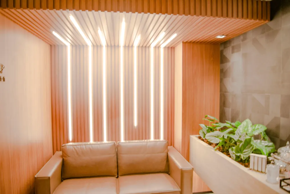 Parede ripada de madeira com iluminação embutida e sofá na sala de espera
